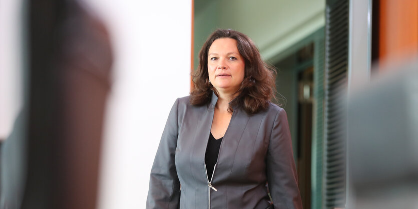 Andrea Nahles, eine Frau mit dunklen Haaren, trägt einen grauen Anzug und betritt einen Raum