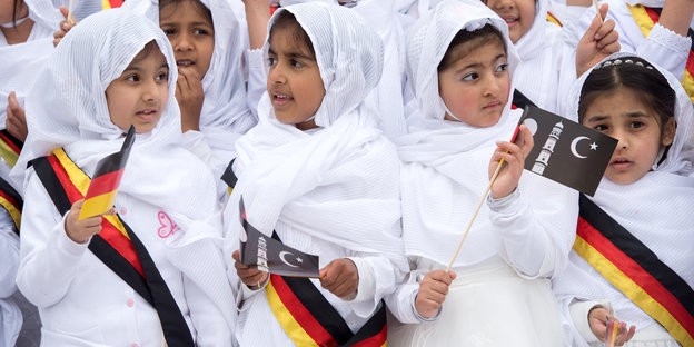 Mädchen mit Kopftüchern und Schärpen in Deutschlandfarben