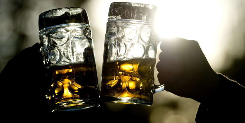 Zwei Menschen stoßen mit Bierkrügen gemeinsam an