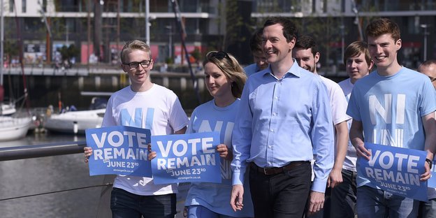 Eine Gruppe von Menschen mit "Vote Remain"-Schildern. Zwischen ihnen läuft ein Mann, es ist George Osborne
