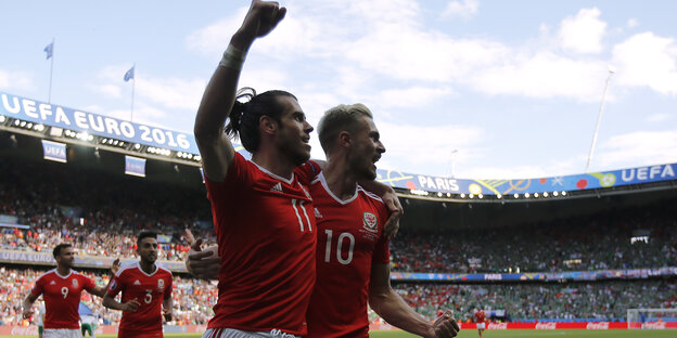 Gareth Bale und Aaron Ramsey feiern zusammen in einem Fußballstadion