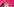 Hilary Benn vor rosafarbenem Hintergrund an einem Rednerpult