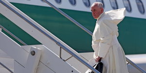 Papst Franziskus, ein älterer Mann in einem weißen Gewand steigt in ein Flugzeug