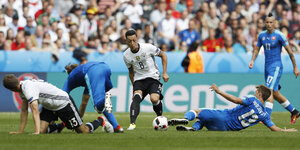 Mesut Özil (Mitte) führt den Ball. Links und rechts von ihm krabbeln Müller und zwei slowakische Spieler über den Rasen