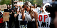 Gina-Lisa Lohfink hält ihre Sonnenbrille fest, im Hintergrund UnterstützerInnen mit Plakaten