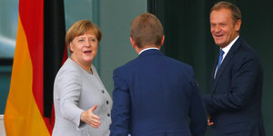Merkel links, Donald Tusk links und ein unbekannter Mann von hinten