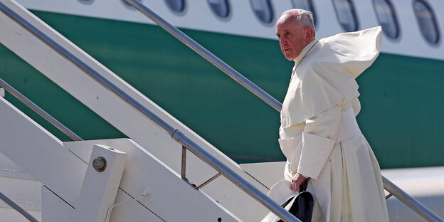 Ein älterer Herr auf einer Gangway zu einem Flugzeug. Es ist der Papst
