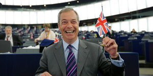 Ukip-Chef Nigel Farage hält im EU-Parlament lachend eine Großbritannienflagge hoch