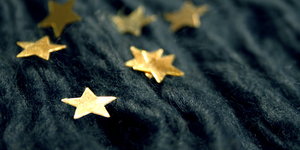 Goldene Sternchen liegen auf einem dunklen Tuch