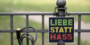 An einem Zaun hängt ein Schild „Liebe statt Hass“