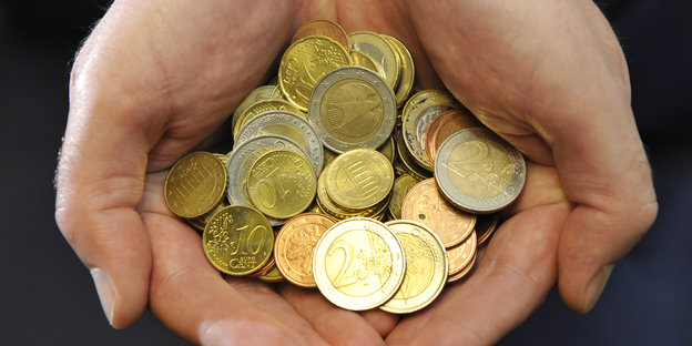 Einige Euromünzen werden von zwei Händen gehalten