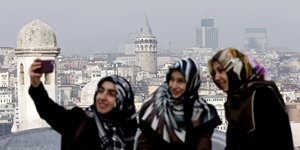 Drei Frauen machen Selfies vor dem Galata-Turm in Istanbul