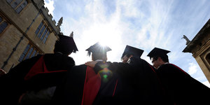 Oxford-Absolventen mit eckigen Hüten schauen in den Himmel