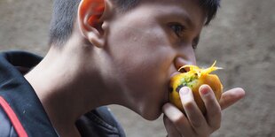 Ein Junge beißt in eine Mango