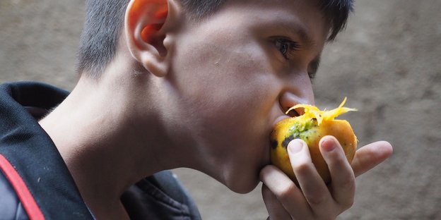 Ein Junge beißt in eine Mango