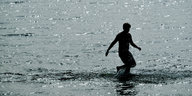 Ein Mann läuft am Wannsee ins Wasser