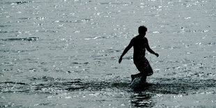 Ein Mann läuft am Wannsee ins Wasser