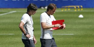 Löw läuft mit Co-Trainer Schneider über den Trainingsplatz. Schneider hält eine Mappe