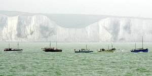 Fischerboote fahren vor den Kreidefelsen von Dover