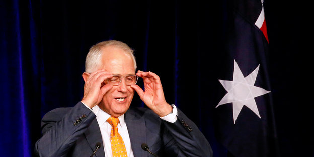 Malcolm Turnbull, ein älterer Mann mit Glatze rückt mit beiden Händen seine Brille zurecht