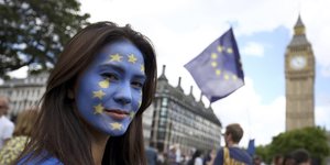 Eine Frau, deren Gesicht mit der Symbolik der EU-Fahne bemalt ist, dahinter der Big Ben