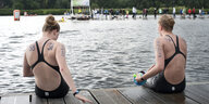 Zwei Schwimmerinnen sitzen auf einem Steg