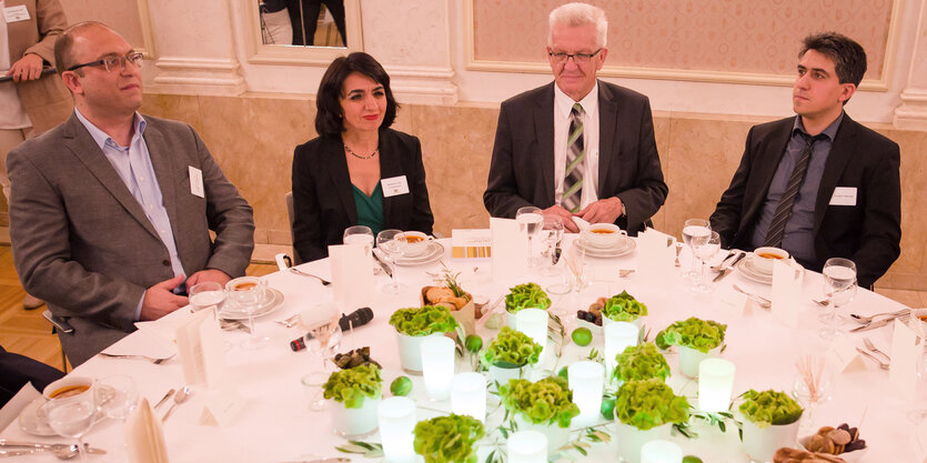 Winfried Kretschmann sitzt mit Gästen beim Fastenbrechen am Tisch