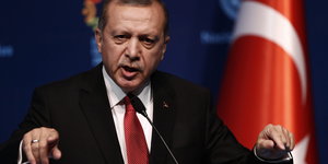 Der türkische Präsident Erdogan gestikuliert bei einer Rede, im Hintergrund die türkische Flagge
