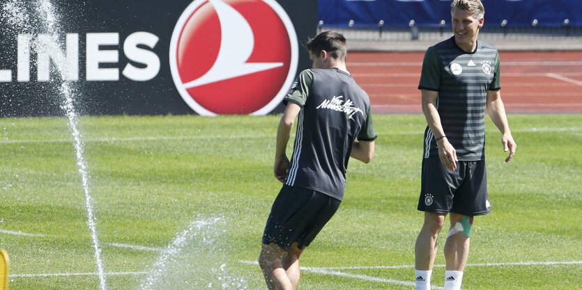 Julian Weigl und Bastian Schweinsteiger neben einem Rasensprenger