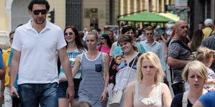 Menschen in Sommerkleidung laufen durch eine Fußgängerzone