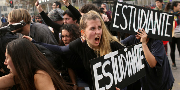 Studenten gehen auf einem Platz und halten Schilder mit der Aufschrift "Estudiante"