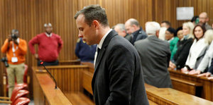 Oscar Pistorius hat sich von seinem Sitz erhoben und hört sich die Verkündung des Strafmaßes an
