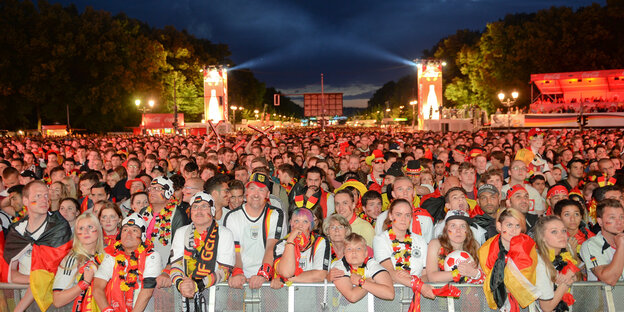 Viele Fans schauen Fußball in deutschland-farbenen Fan-Utensilien