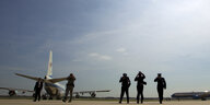 Soldaten halten ihre Hüte fest, als ein Flugzeug hinter ihnen startet