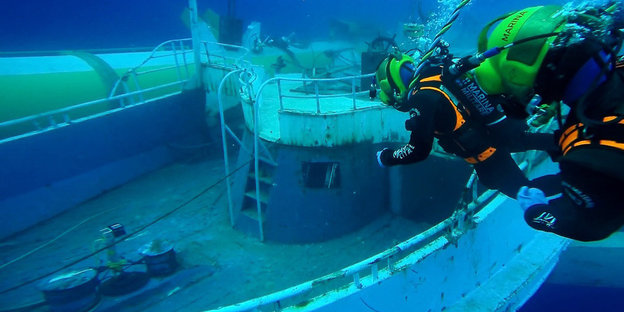 Unterwasseraufnahme von Tauchern vor einem gesunkenen Schiff