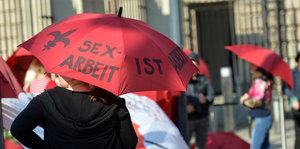 Menschen mit Regenschirmen, auf einem steht „Sexarbeit ist Arbeit“