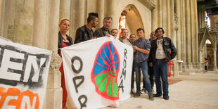 Vor dem Dom stehen mehrere Menschen, die Transparente halten