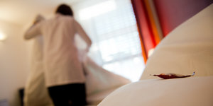 Ein Mensch macht Betten in einem Hotelzimmer