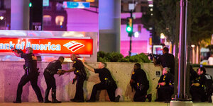 US-Polizisten stehen und hocken in einer Reihe hinter einer Mauer der „Bank of America“