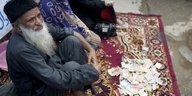 Abdul Sattar Edhi sitzt auf einem Teppich mit Geldscheinen vor sich