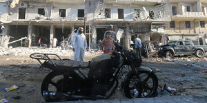 Nach einem Luftangriff sehen sich Bewohner die zerstörten Fassaden an