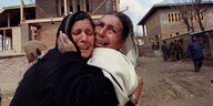 Zwei Frauen in Gewändern liegen sich weinend in den Armen