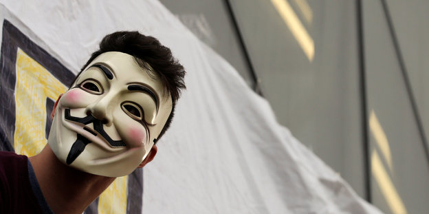 Jemand trägt eine Guy-Fawkes-Maske auf einer Demo in Madrid