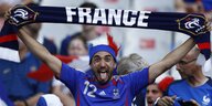 Französischer Fan streckt die Zunge raus und hält einen Schal in die Luft