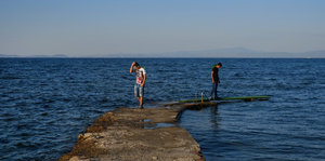 Zwei Männer stehen auf einer Mauer am Meer
