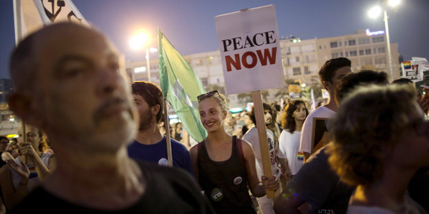 Eine Demo, auf der jemand ein Schild mit der Aufschrift "Peace Now" hochhält