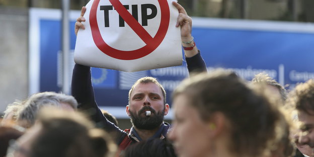Protestler, darunter ein Mann mit einem Plakat mit einem durchgestrichenen TTIP