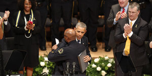 Obama und der Polizeichef umarmen sich, im Hintergrund klatschen Menschen