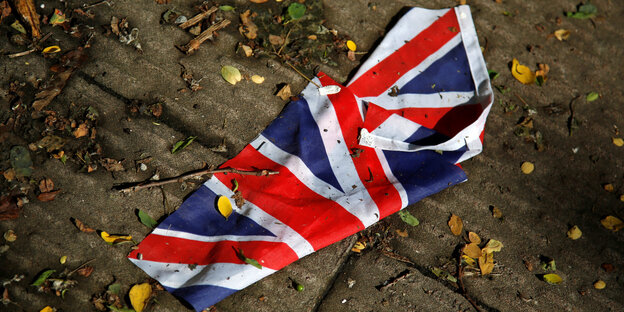 Eine britische Flagge liegt auf dem Boden zwischen Blättern und Ästen