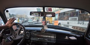 Ein US-Fähnchen baumelt am Rückspiegel im Innern eines kubanischen Autos